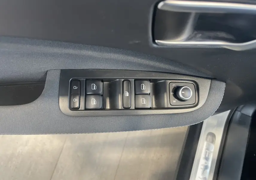 Gros plan sur les commandes de lève-vitres et rétroviseurs sur la porte côté conducteur d'une LEAPMOTOR T03 Luxury blanche.