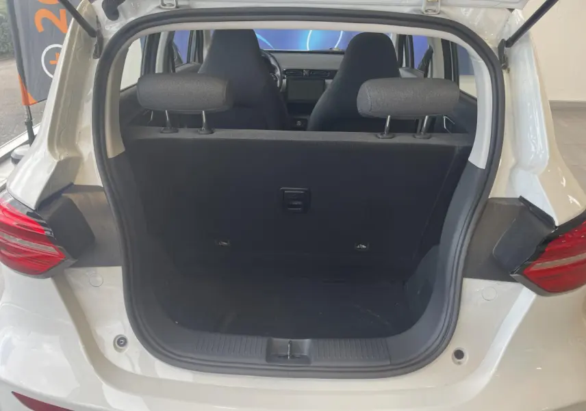 Vue arrière du coffre ouvert d'une LEAPMOTOR T03 Luxury blanche, montrant l'intérieur et les sièges avant.