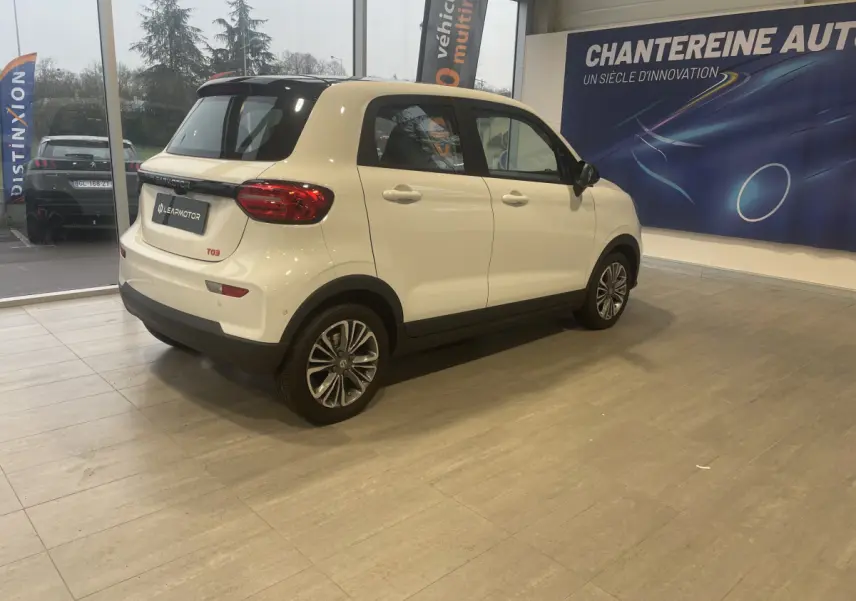 Vue 3/4 arrière droite du LEAPMOTOR T03 blanc, version Luxury, avec toit noir et jantes alliage en showroom.