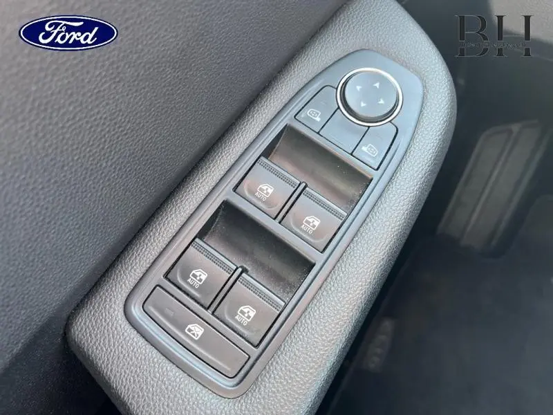 Gros plan sur les commandes de lève-vitres et rétroviseurs côté conducteur d'une Renault Clio gris platine, intérieur noir.