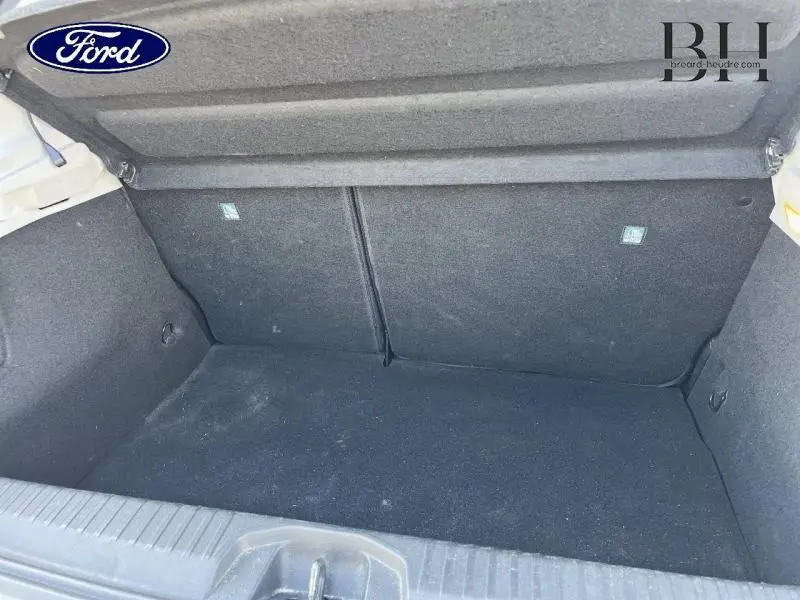 Coffre ouvert vu de l'arrière, intérieur noir, sans chargement, avec banquette arrière rabattable visible.