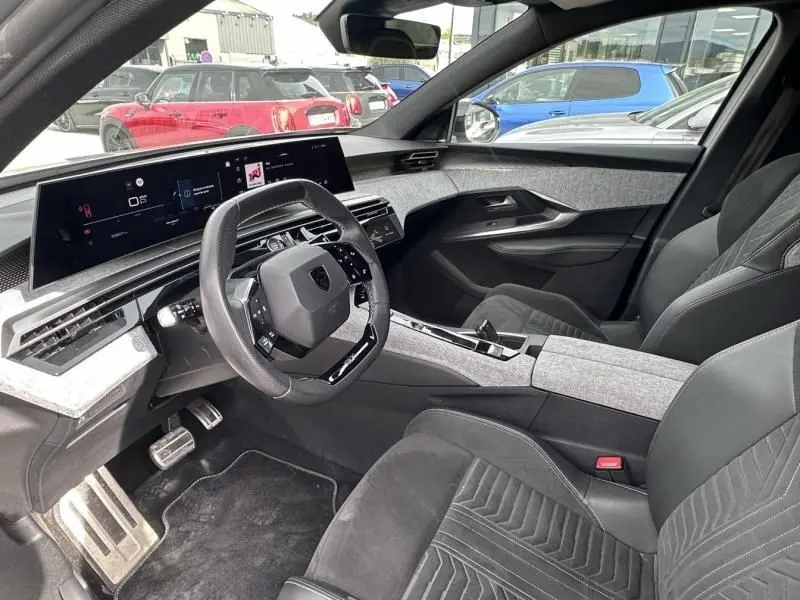 Vue intérieure côté conducteur du Peugeot 3008 2024 gris métal, mettant en valeur le tableau de bord numérique et les sièges en tissu et cuir.