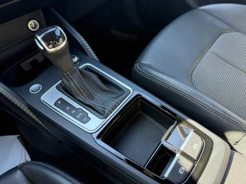 Gros plan sur la console centrale de l'Audi Q2 35 TDI S line 2025 avec levier de vitesse automatique et sellerie cuir grise.