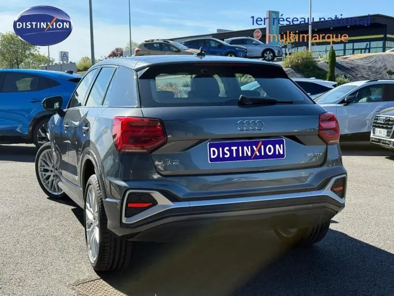 Audi Q2 35 TDI S line gris Daytona nacré, vue 3/4 arrière droit, avec feux arrière LED et jantes alliage.