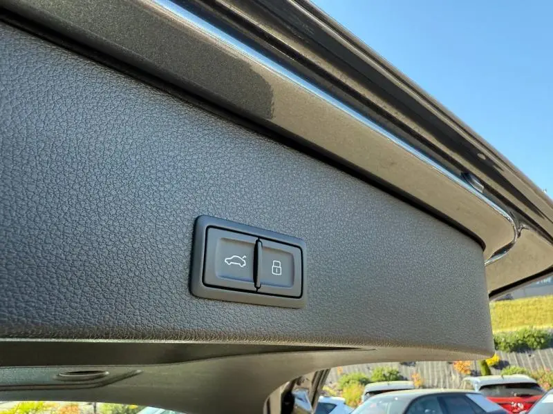 Gros plan sur les boutons d'ouverture et de verrouillage du hayon du coffre du coffre gris Daytona nacré d'un Audi Q2 2025.