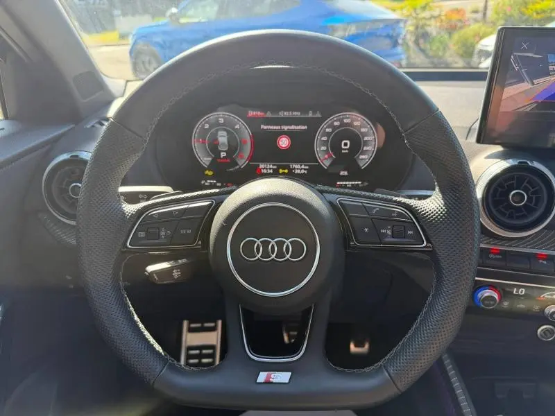 Vue intérieure centrée sur le volant perforé S line d'un Audi Q2 35 TDI 2025 avec tableau de bord numérique.