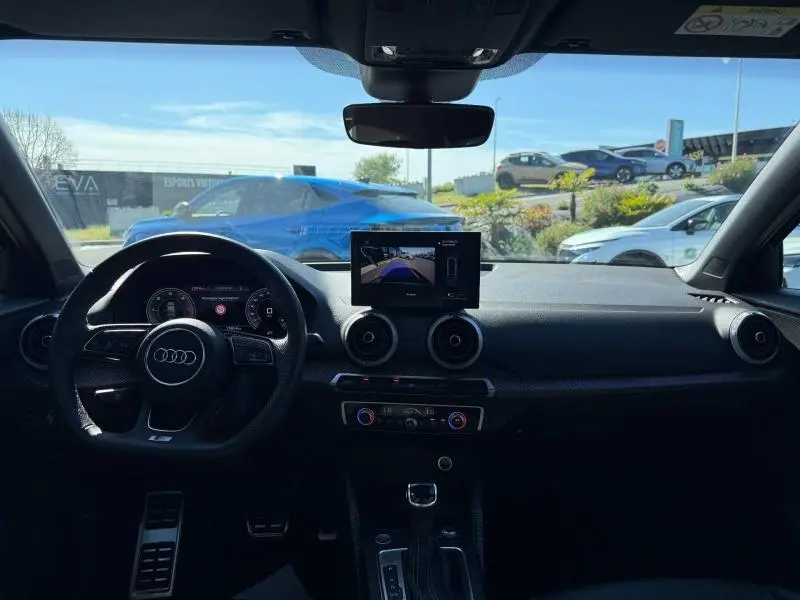 Vue intérieure de l'Audi Q2 35 TDI S line 2025, tableau de bord et écran central avec caméra de recul visible.
