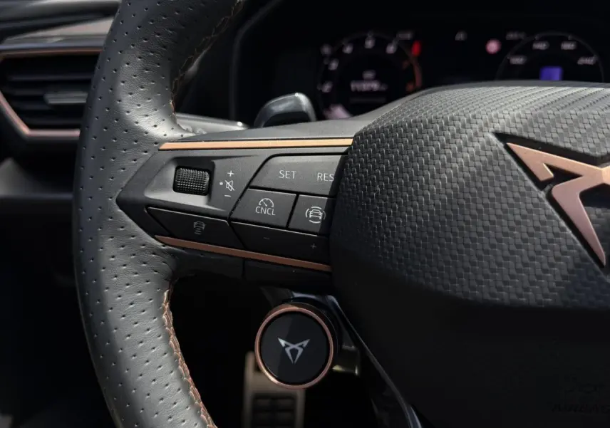 Gros plan sur le volant cuir perforé noir avec logo CUPRA cuivré et commandes multifonctions du Formentor 2025.