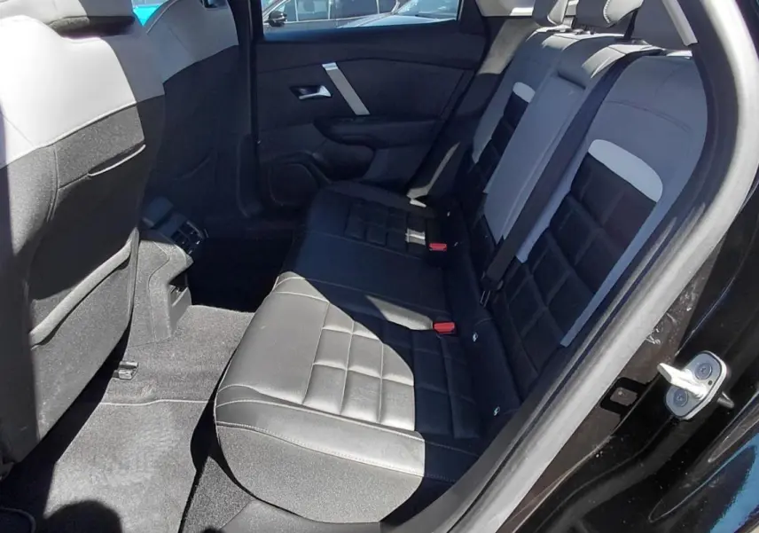 Vue intérieure côté droit des sièges arrière en cuir noir et gris du Citroën C4 X hybride 2025 avec porte ouverte.