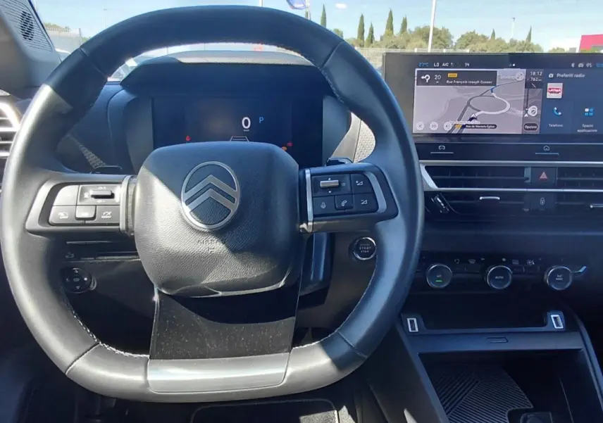 Vue intérieure centrée sur le volant cuir noir et le tableau de bord numérique du Citroën C4 X hybride 2025.