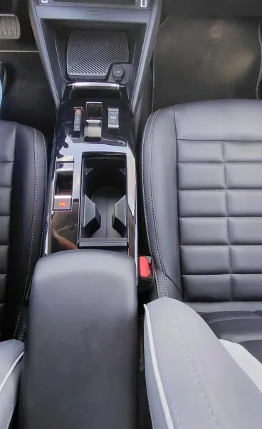 Vue plongeante de la console centrale noire du Citroën C4 X hybride 2025 avec accoudoir cuir et sièges en cuir noir.