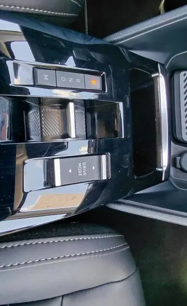 Vue plongeante sur la console centrale noire brillante du Citroën C4 X hybride 2025 avec commandes boîte auto et mode de conduite.