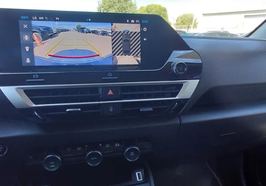 Vue intérieure du tableau de bord du Citroën C4 X noir 2025, avec écran tactile affichant la caméra de recul et commandes climatisation.