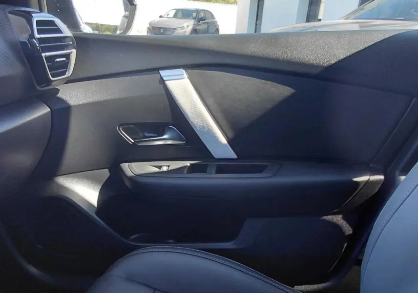 Vue intérieure côté passager avant de la Citroën C4 X 2025, montrant la porte noire et le siège en cuir gris.