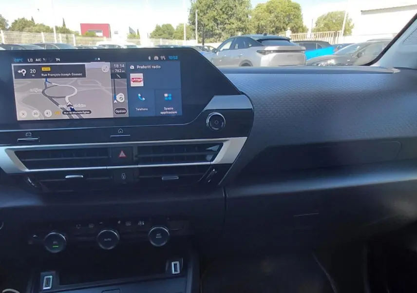 Vue intérieure du tableau de bord de la Citroën C4 X hybride 2025 avec écran tactile et commandes de climatisation.