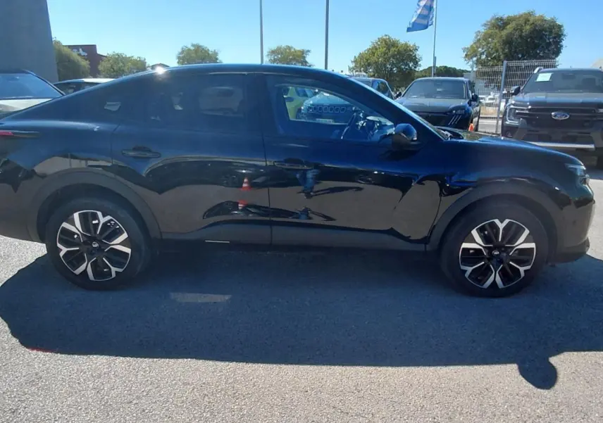 Profil côté gauche d'une Citroën C4 X noire 2025 avec jantes alliage 17 pouces, toit ouvrant panoramique visible.
