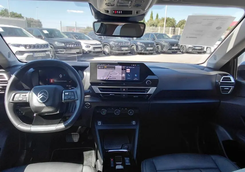 Vue intérieure avant du Citroën C4 X noir 2025, mettant en valeur le tableau de bord digital et le volant cuir.