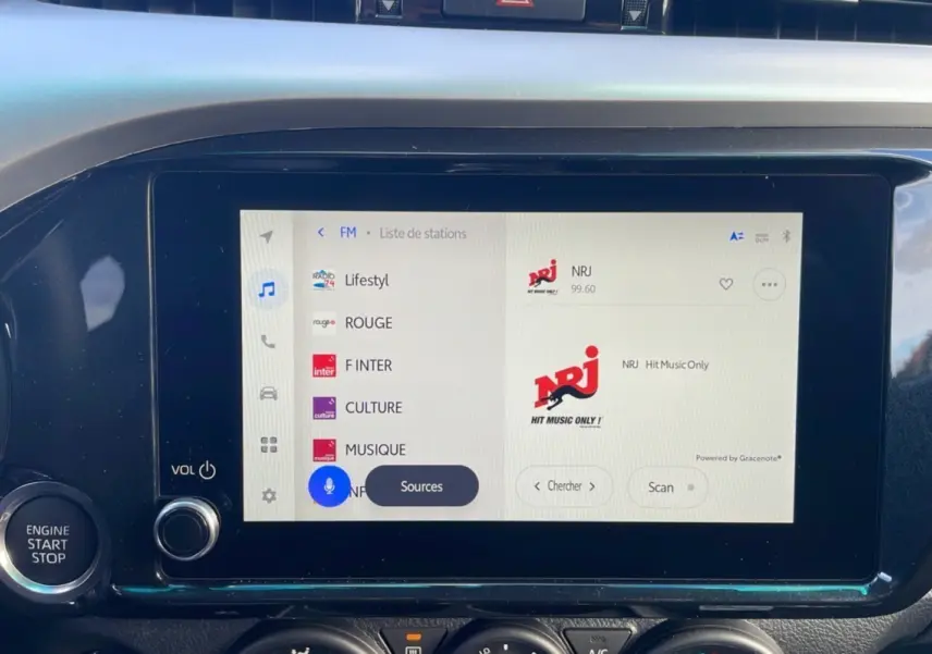 Écran tactile multimédia allumé du Toyota Hilux 2025, avec bouton moteur et commandes audio visibles.
