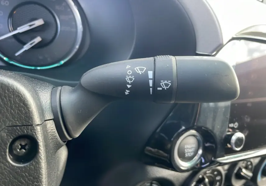 Gros plan sur la commande d'essuie-glace du Toyota Hilux 2025, avec tableau de bord et bouton start/stop visibles.