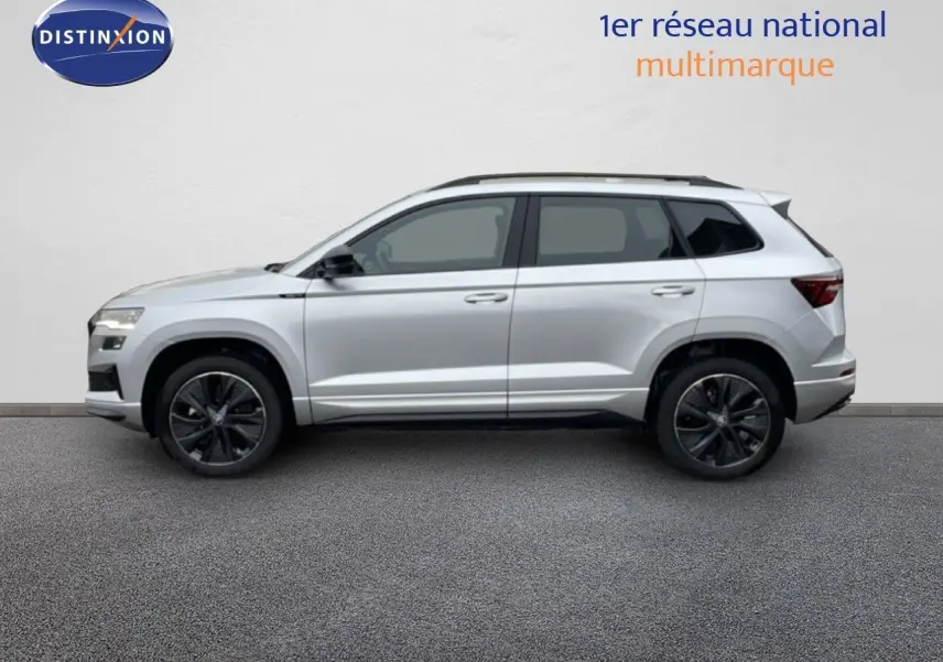 Profil côté gauche d’un Skoda Karoq gris argent métallisé 2025 avec jantes noires et toit ouvrant panoramique.