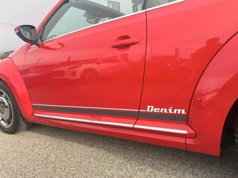 Vue latérale côté gauche d'une Volkswagen Coccinelle Cabriolet rouge 2016 avec logo Denim sur la porte.