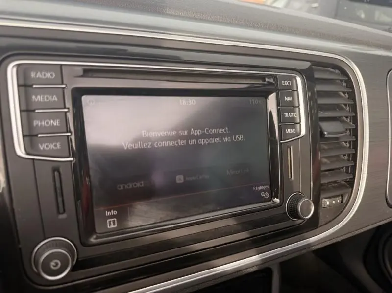 Écran central tactile du Volkswagen Coccinelle Cabriolet rouge 2016, vue rapprochée du tableau de bord.
