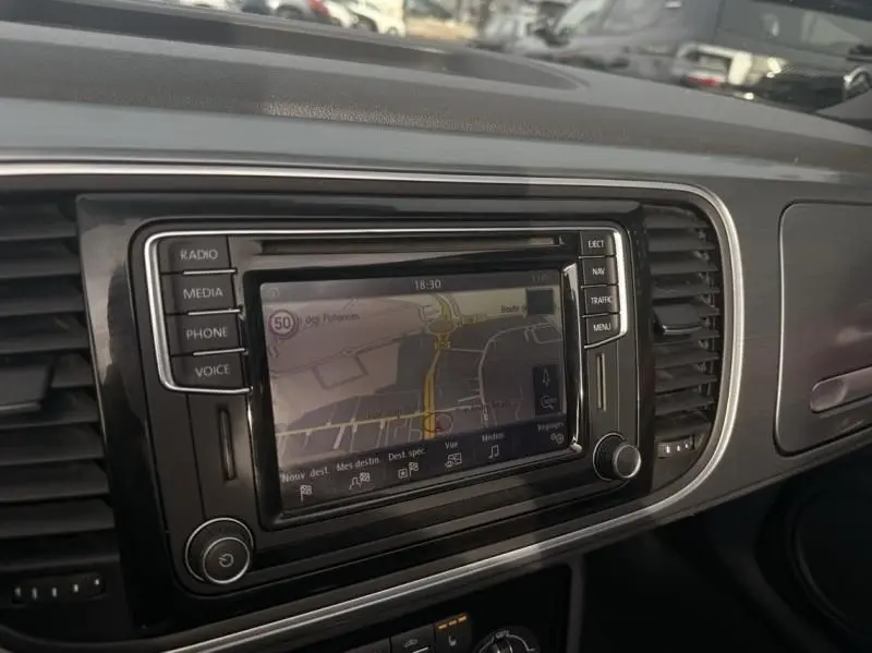 Vue intérieure du tableau de bord de la Volkswagen Coccinelle Cabriolet 2016, écran de navigation central en fonctionnement.