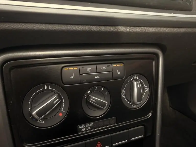 Gros plan sur les commandes de climatisation et sièges chauffants du tableau de bord d’une Volkswagen Coccinelle Cabriolet rouge 2016.