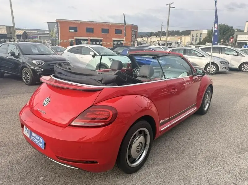 Vue 3/4 arrière droite d'une Volkswagen Coccinelle Cabriolet rouge 2016 avec capote ouverte et jantes spécifiques Denim.