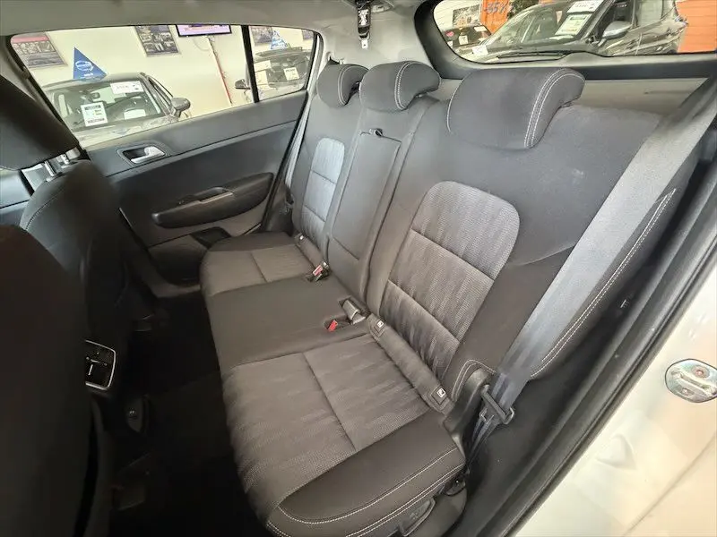 Vue intérieure côté droit des sièges arrière noirs du Kia Sportage blanc 2021, avec ceinture de sécurité visible.