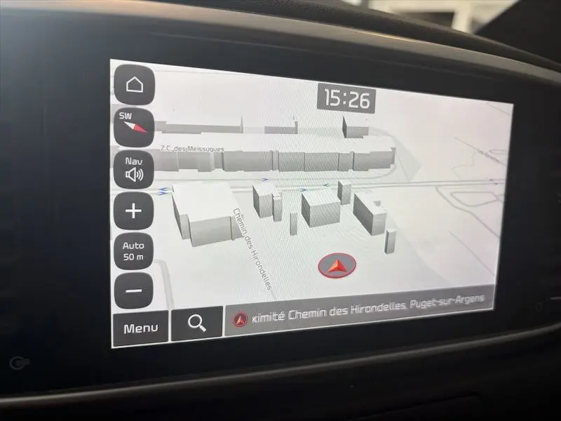 Écran de navigation 3D du Kia Sportage blanc, vue intérieure sur la carte avec interface tactile et heure affichée.