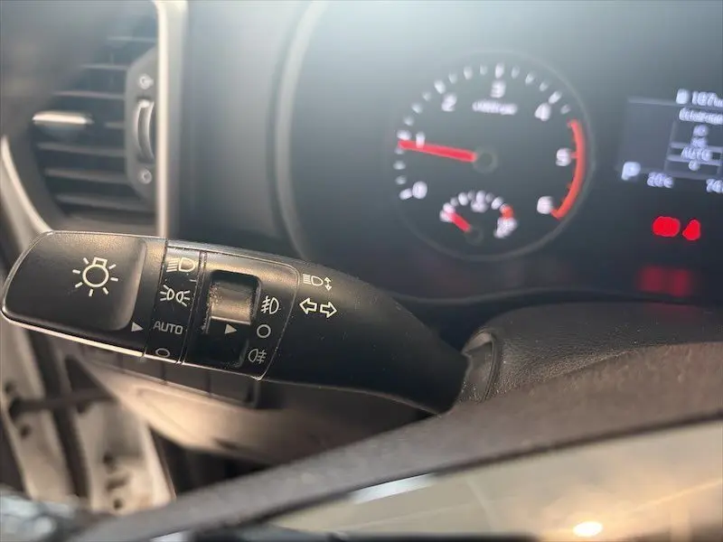 Gros plan sur la manette de clignotants et phares à gauche du volant dans l'habitacle d'un Kia Sportage blanc 2021.