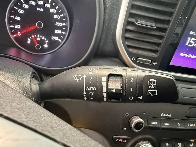 Gros plan sur la manette d'essuie-glace du tableau de bord d'un KIA Sportage blanc, avec affichage digital partiel.