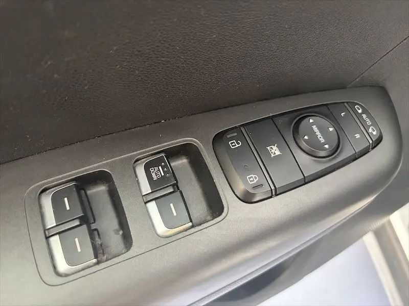 Gros plan sur les commandes de vitres et rétroviseurs côté gauche intérieur d'un KIA SPORTAGE blanc 2021.