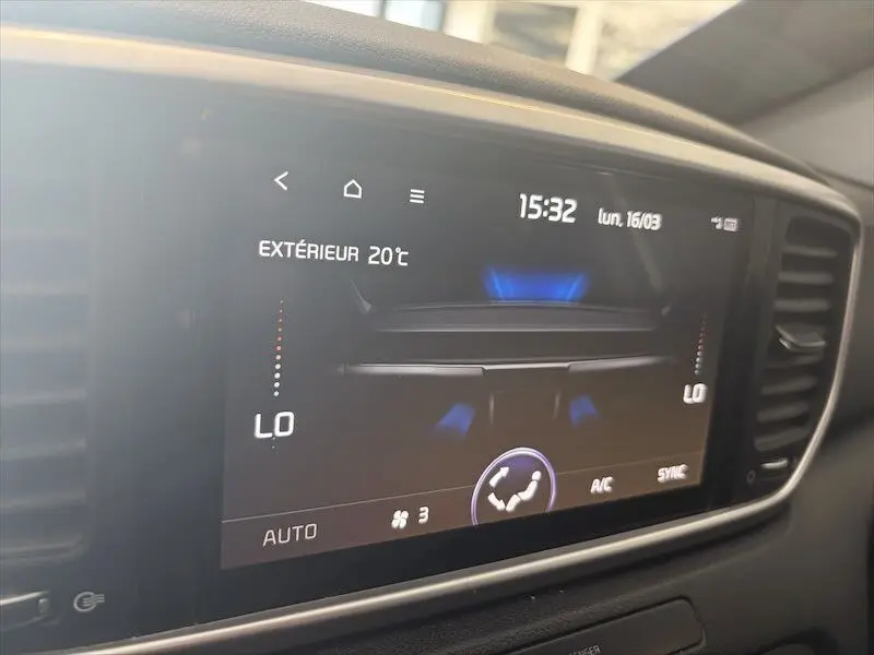 Écran tactile du système de climatisation du Kia Sportage blanc, affichant la température extérieure et réglages en mode automatique.