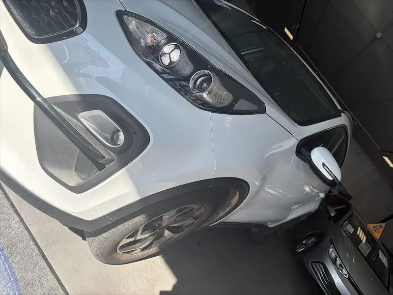 Vue avant gauche rapprochée d'un KIA Sportage blanc 2021 avec phares LED et jantes noires bicolores.