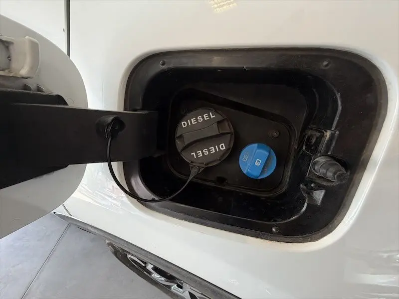 Détail de la trappe à carburant blanche du Kia Sportage 2021, montrant bouchons diesel et additif bleu.