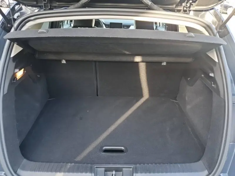 Coffre ouvert vu de l'arrière du Renault Captur bleu marine fume avec cache-bagages et intérieur noir.