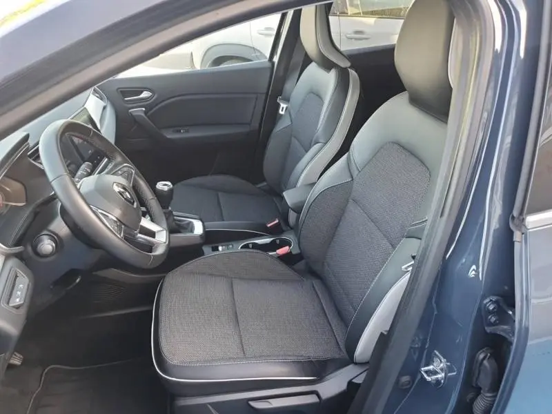 Vue intérieure côté conducteur du Renault Captur bleu marine, sièges tissu et cuir noir avec surpiqûres grises.