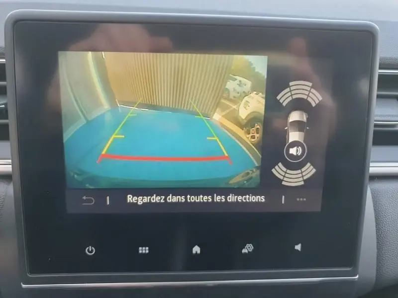 Écran de caméra de recul du Renault Captur 2023 montrant l’arrière avec lignes de guidage colorées et parking bleu visible.