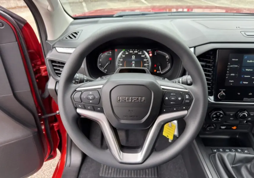 Vue intérieure centrée sur le volant multifonctions noir de l'Isuzu D-MAX 2026 avec tableau de bord et écran tactile.