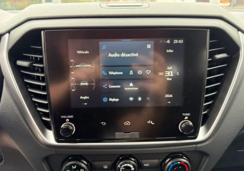 Écran tactile central de l’Isuzu D-MAX 2026 affichant le menu audio et connectivité, entouré de commandes de climatisation.