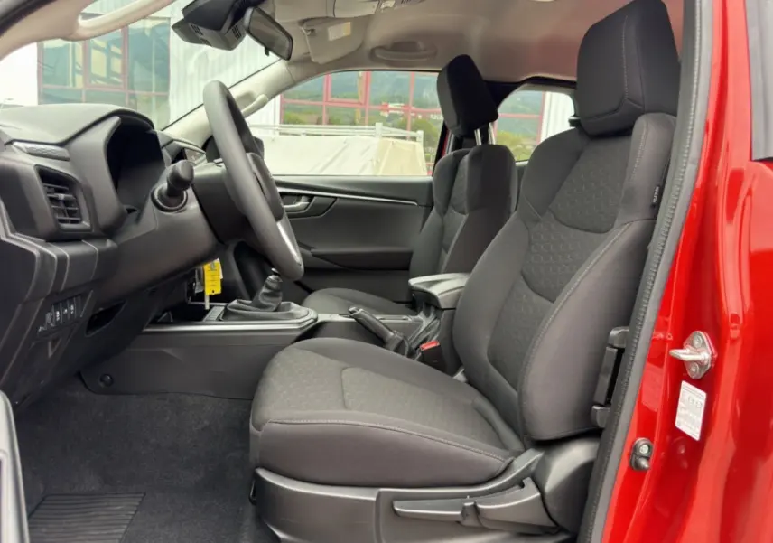 Vue intérieure côté conducteur du pick-up Isuzu D-MAX 2.2 TD 164 avec sièges tissu noirs et porte ouverte rouge.