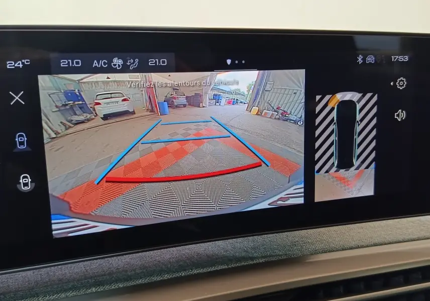 Écran tactile intérieur montrant la caméra de recul et l’aide au stationnement du Peugeot 5008 gris clair, vue arrière.