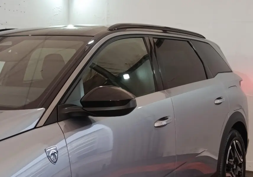 Vue latérale droite du Peugeot 5008 gris clair 2026 avec logo lion et vitres teintées dans un garage.
