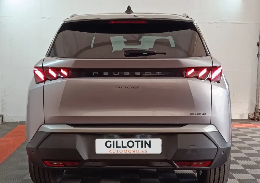 Vue arrière d'un Peugeot 5008 gris clair 2026 avec feux LED allumés et badge Plug-in visible.