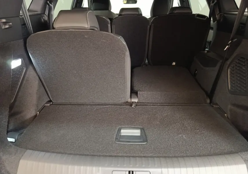 Vue arrière du coffre du Peugeot 5008 gris clair avec sièges rabattus partiellement pour agrandir l'espace de chargement.