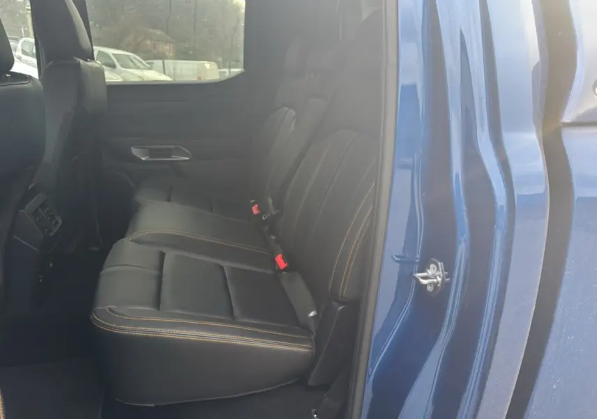 Vue intérieure côté gauche sur la banquette arrière en cuir noir avec surpiqûres orange du Ford Ranger Wildtrak bleu lightning.