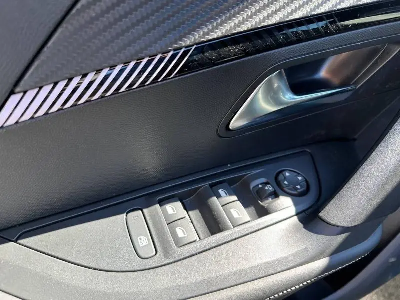 Gros plan sur la commande des vitres et la poignée intérieure côté gauche d’une Peugeot 2008 1.2 Hybrid 145ch Allure 2025.