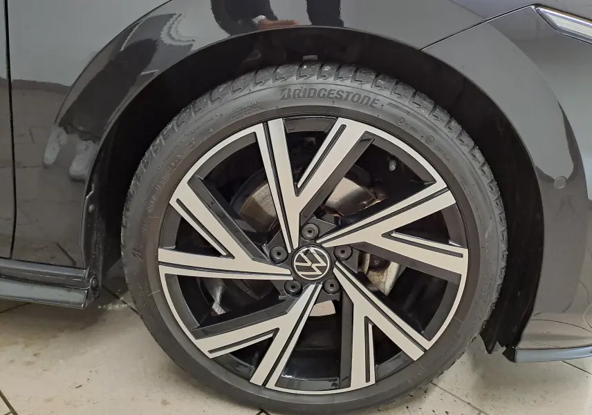 Gros plan sur la jante alliage bicolore noire et argentée de la Volkswagen Golf 1.5 eTSI noire intense nacrée.